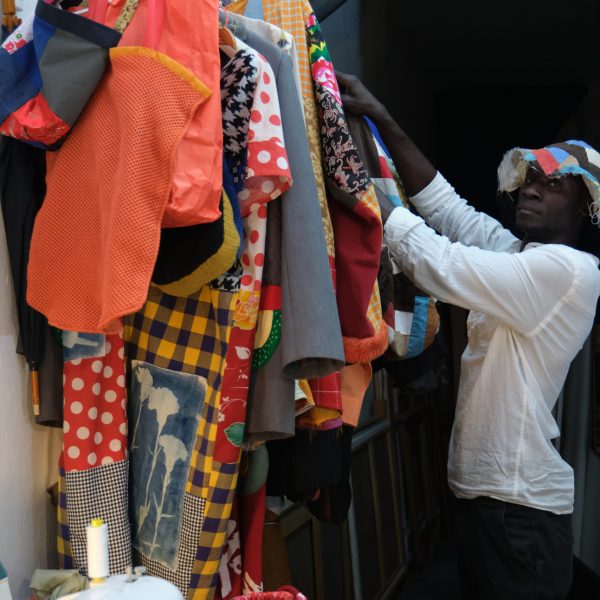 Black man choosing an african item of clothing to wear. African tailor in his sewing workshop.